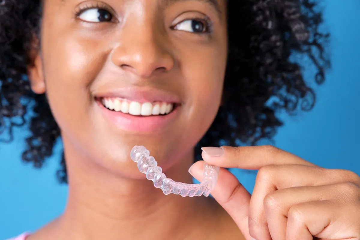 Person smiling confidently with straight, aligned teeth after Invisalign treatment
